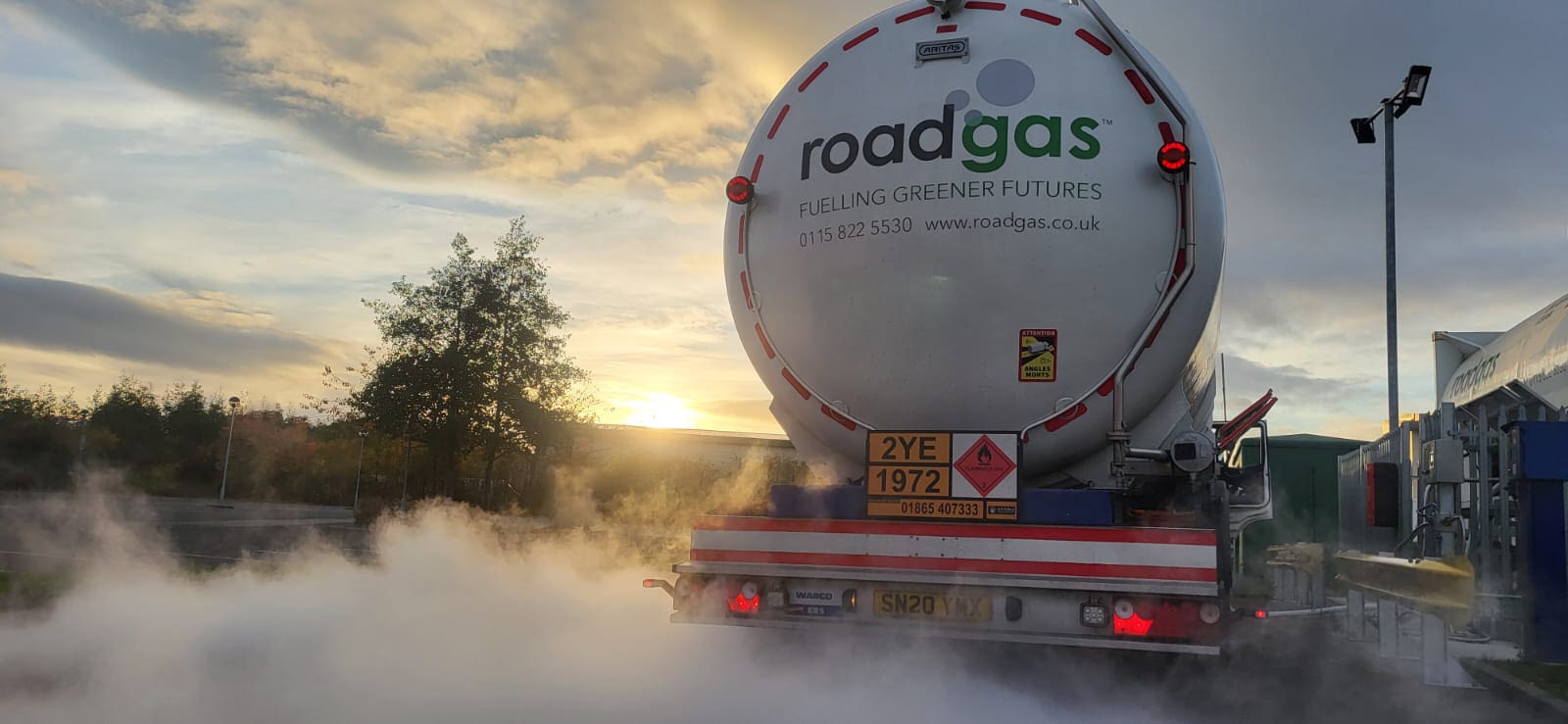 A Roadgas truck used for Bio-LNG refuelling emitting vapor during a sunset, highlighting renewable gas transport solutions.